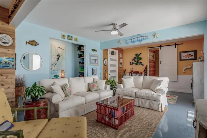 Ground floor bonus room featuring cedar and wood shiplap walls, a barn door, storage shelfing, and ceiling fan