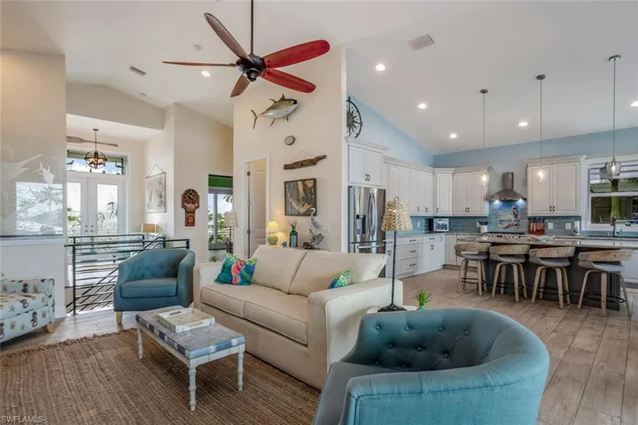 Living room with french doors, porcelain plank tile  flooring, high vaulted ceiling, and ceiling fan