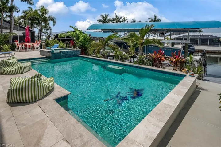 View of saltwater swimming pool featuring a travertine marble pool patio, automatic pool cleaner, and an in ground spa