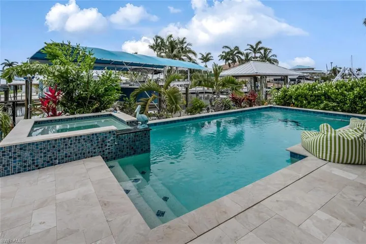 View of saltwater swimming pool featuring an in ground hot tub and travertine marble pool deck