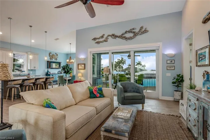 Living room, kitchen/dining area, access to outside screened balcony, and ceiling fan with notable chandelier