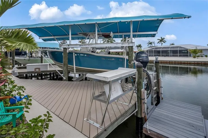 View of synthetic lumber dock featuring a covered boat lift, fish cleaning table, floating dock on canal