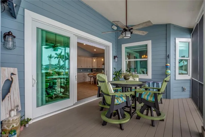 Screened upstairs balcony patio with synthetic lumber deck floors featuring ceiling fan and roller shades