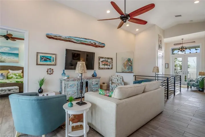 Living room with vaulted ceiling, ceiling fan, and french doors