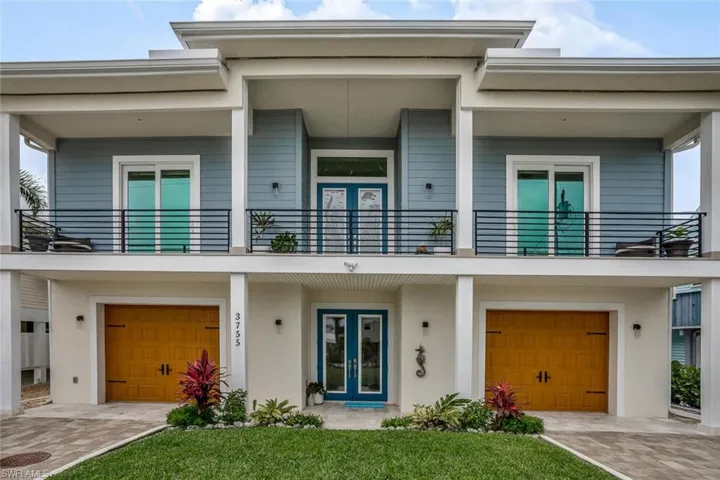 Front elevation of house with two separate garages, french doors and a balcony