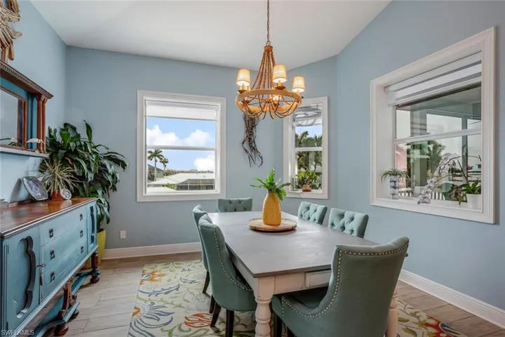 Dining room featuring a notable chandelier, window shades and porcelain plank tile flooring