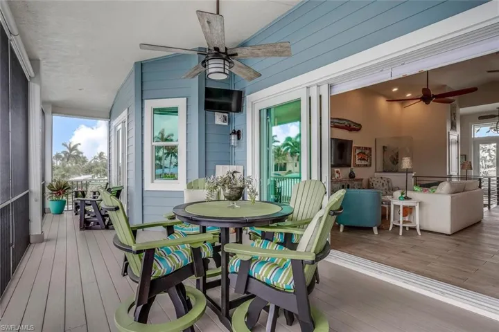 Screened upstairs balcony porch featuring ceiling fan, synthetic lumber deck flooring