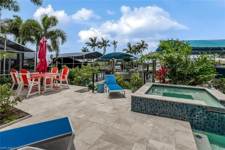 View of terrace featuring a water view, a lanai, lime trees, and an in ground hot tub