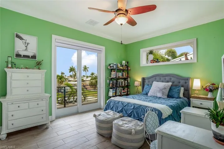 Bedroom featuring porcelain plank tile flooring, ceiling fan, crown molding, window shade, and access to outside balcony