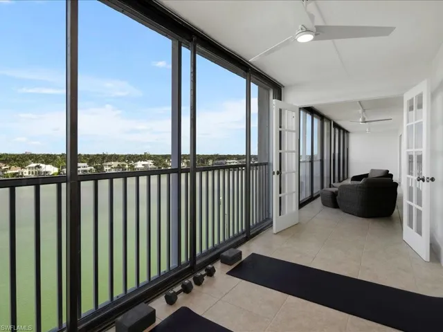 Sunroom featuring a water view, tile patterned flooring, french doors, and a wall of windows