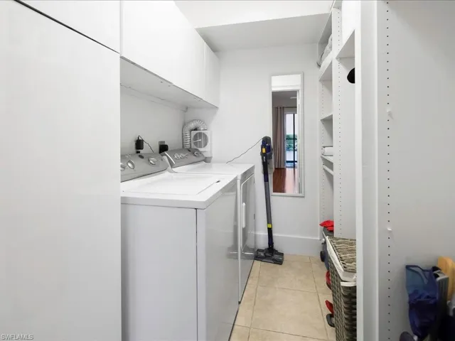 Laundry area with light tile patterned floors, independent washer and dryer, and cabinet space