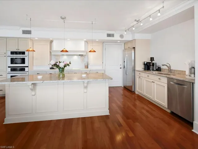 Kitchen featuring decorative light fixtures, light stone counters, stainless steel appliances, tasteful backsplash, and a center island