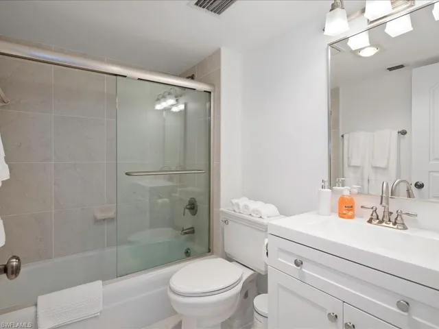 Bathroom with vanity and combined bath / shower with glass door