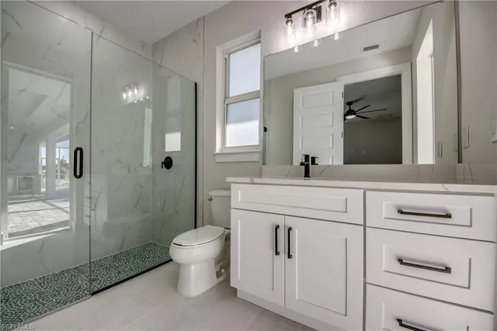 Bathroom with a marble finish shower, vanity, and a ceiling fan