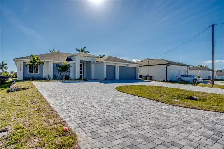 View of front facade with a front yard, decorative driveway, an attached garage, and stucco siding