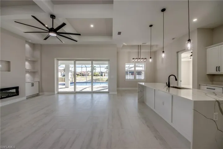 Unfurnished living room with ceiling fan, built in features, a glass covered fireplace, beam ceiling, and coffered ceiling