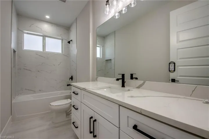 Full bath with vanity and a combined bath / shower with marble appearance