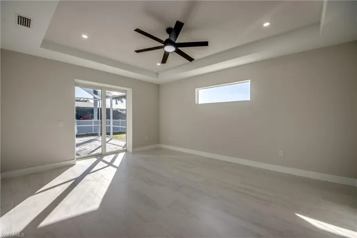 Empty room with a tray ceiling, plenty of natural light, a ceiling fan, and recessed lighting