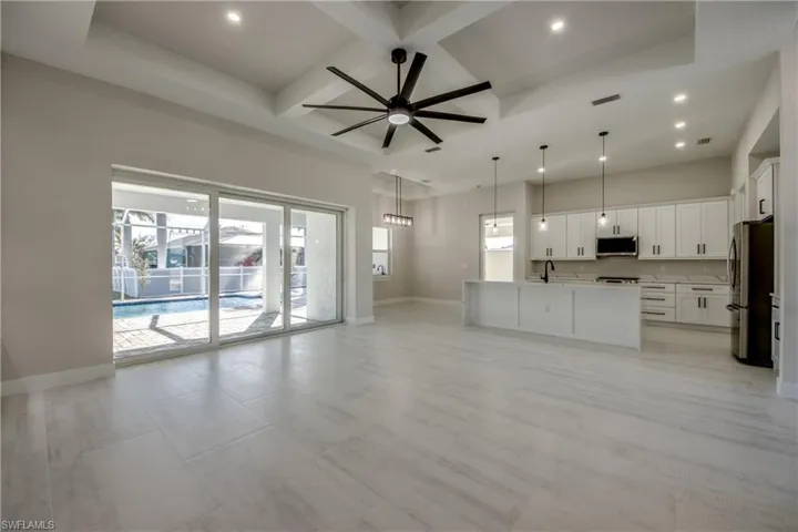Unfurnished living room featuring coffered ceiling, a ceiling fan, beam ceiling, and recessed lighting