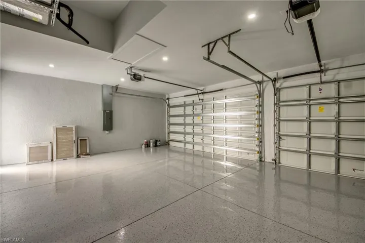 Garage with a garage door opener, recessed lighting, and electric panel
