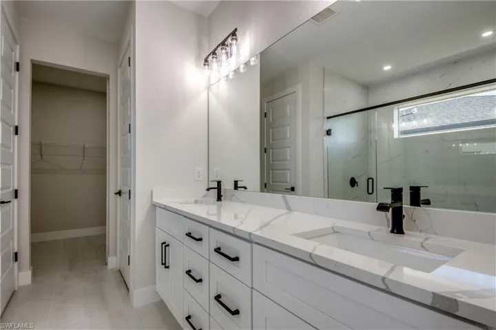 Full bathroom with double vanity, a marble finish shower, and a walk in closet
