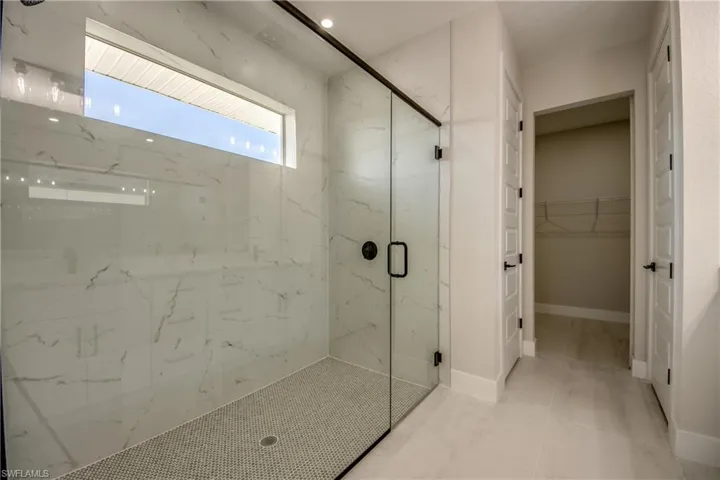 Bathroom with a walk in closet and a marble finish shower
