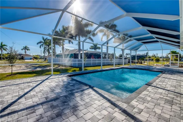 Swimming pool featuring glass enclosure, a patio, and a sunroom