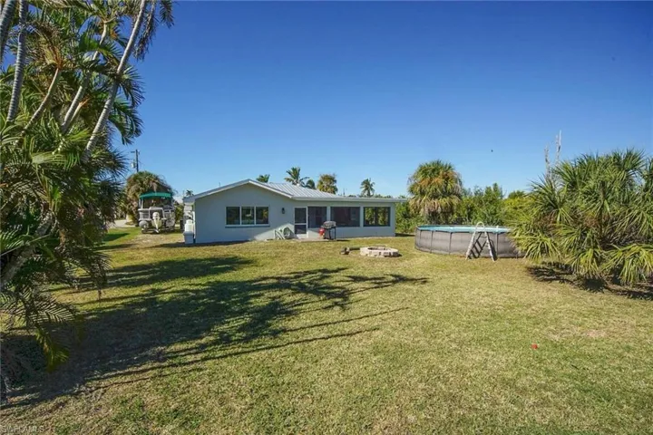 Back of property with an outdoor pool, a lawn, and a sunroom
