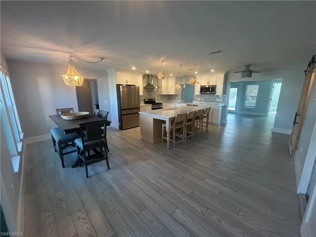 Large kitchen/dining area with stainless steel appliances, backsplash, and a kitchen island