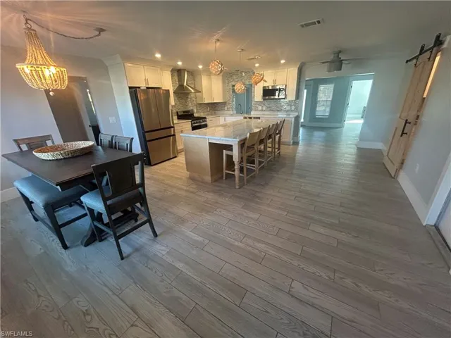 Large kitchen/dining area with stainless steel appliances, tasteful backsplash, and a center island