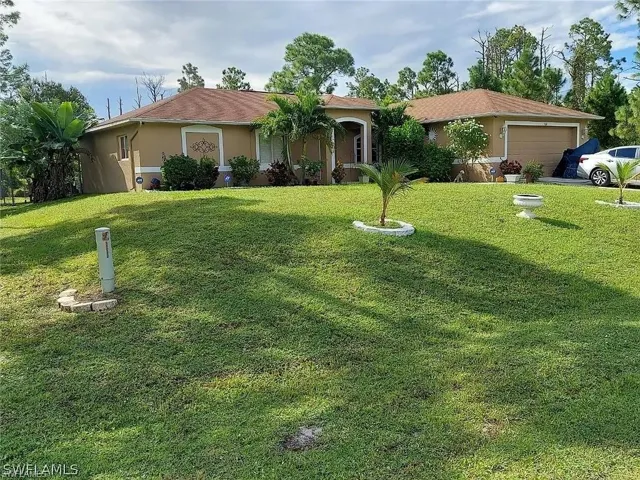 Exterior stucco residence featuring a brown shingle roof, attached garage, and a lush green lawn