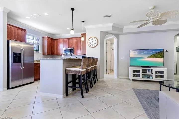 Kitchen with pendant lighting, light tile patterned flooring, a kitchen breakfast bar, and appliances with stainless steel finishes