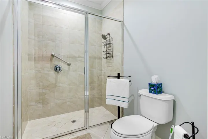 Bathroom with ornamental molding, toilet, and walk in shower