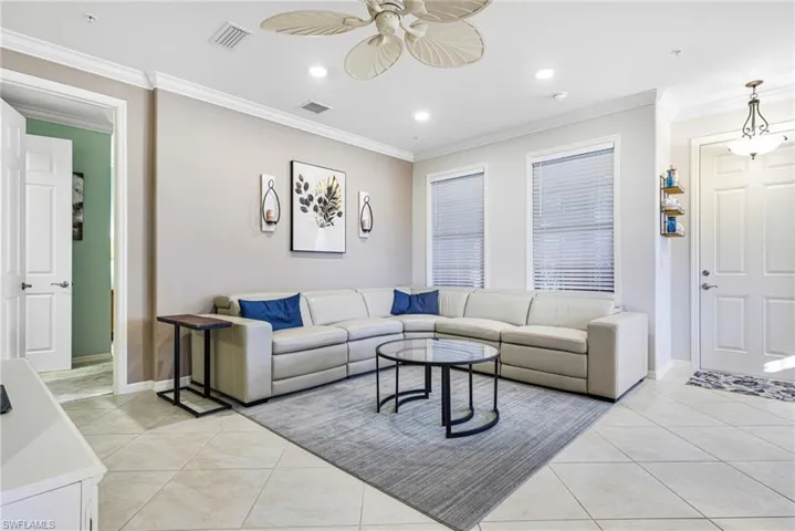 Tiled living room featuring crown molding and ceiling fan