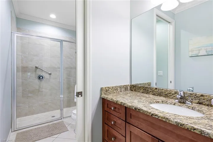 Bathroom featuring walk in shower, toilet, crown molding, vanity, and tile patterned flooring
