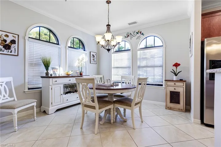 Tiled dining area with a notable chandelier, plenty of natural light, and ornamental molding