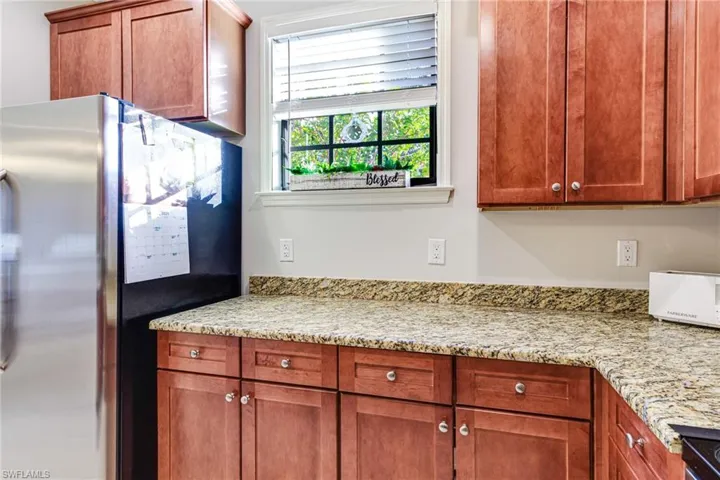 Kitchen with stainless steel fridge and light stone countertops