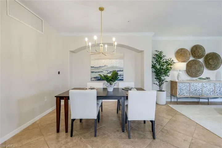 Tiled dining area with a chandelier, crown molding, and baseboards