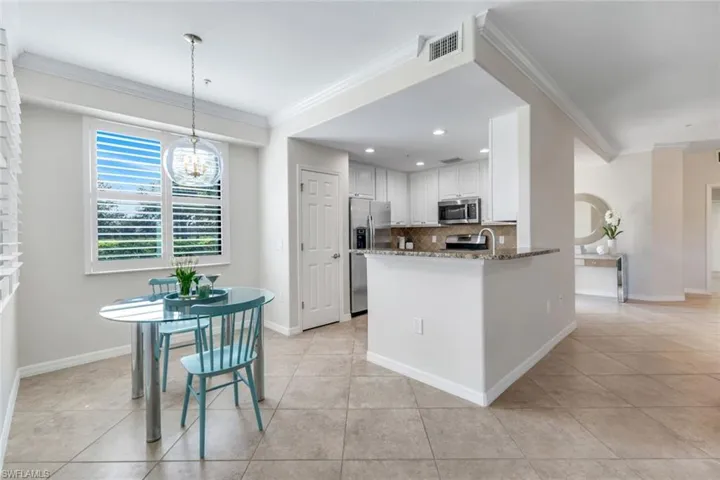 Kitchen featuring appliances with stainless steel finishes, tasteful backsplash, ornamental molding, stone counters, and light tile patterned flooring