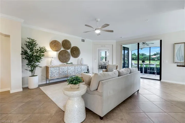 Living area with ceiling fan, plenty of natural light, ornamental molding, and light tile patterned flooring