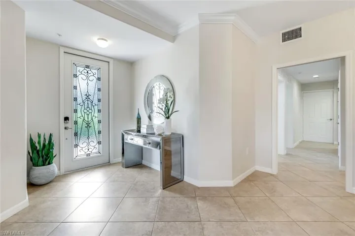 Entrance foyer with light tile patterned floors, ornamental molding, and baseboards