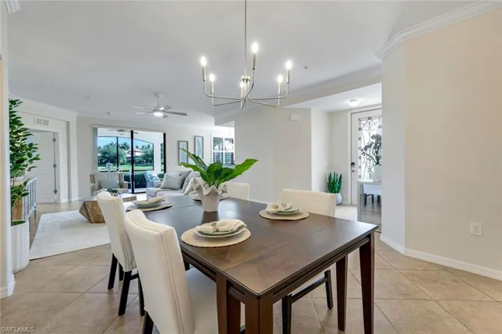 Dining area featuring ornamental molding, a chandelier, ceiling fan, light tile patterned flooring, and baseboards