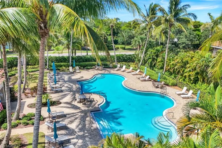 Community pool featuring a patio area and view of wooded area