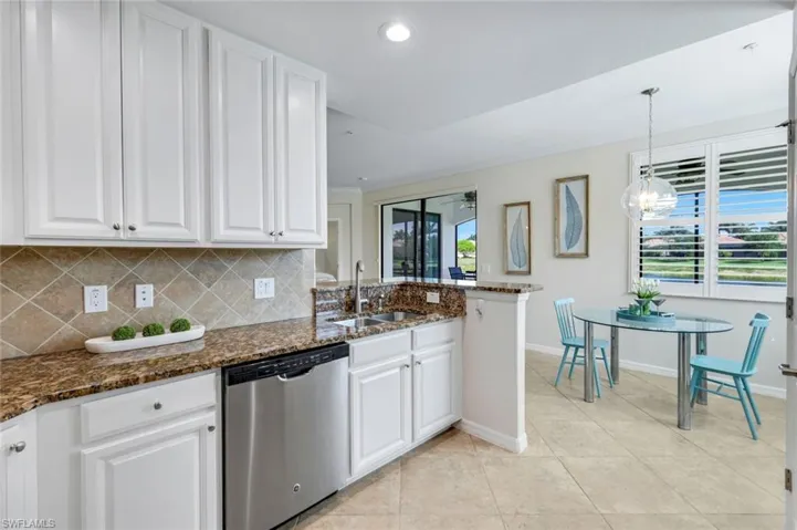 Kitchen with stainless steel dishwasher, a sink, white cabinets, baseboards, and recessed lighting