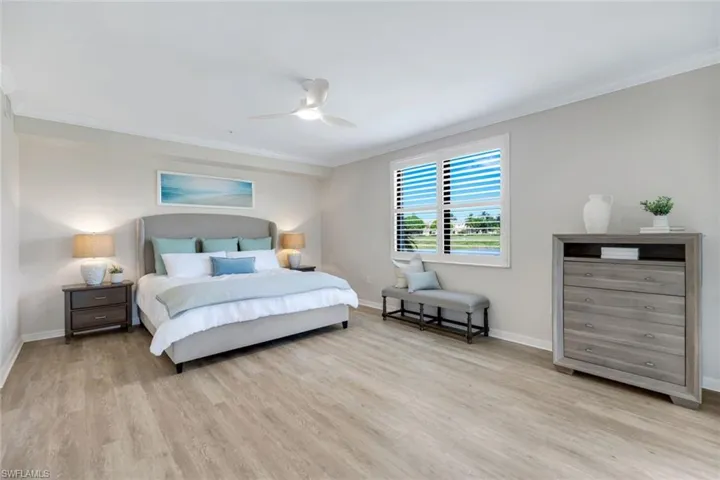 Bedroom with crown molding, light wood finished floors, baseboards, and ceiling fan