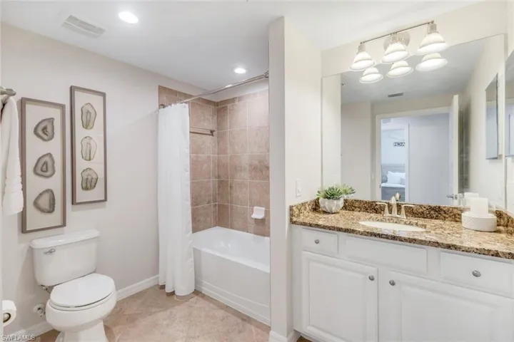 Bathroom with baseboards, shower / tub combo with curtain, vanity, toilet, and tile patterned floors