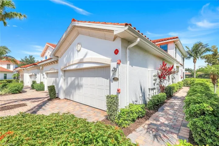 View of side of property with an attached garage, stucco siding, a tile roof, and driveway