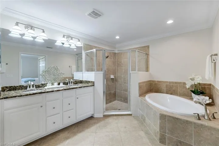 Primary bathroom featuring a stall shower, a garden tub, double vanity, tile patterned floors, and recessed lighting