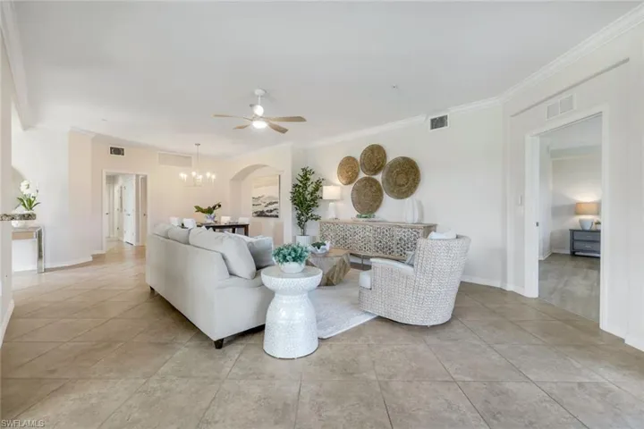 Living area with ceiling fan, a chandelier, ornamental molding, arched walkways, and baseboards