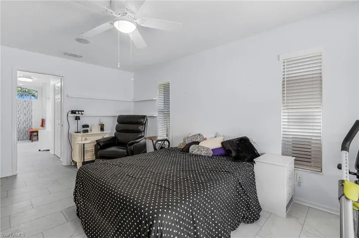 Bedroom featuring ceiling fan and south facing windows and access to large primary bath and 2 walk in closets